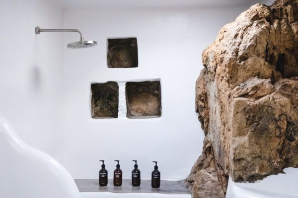 Keli Serifos bathroom with natural rock and Grown Alchemist toiletries