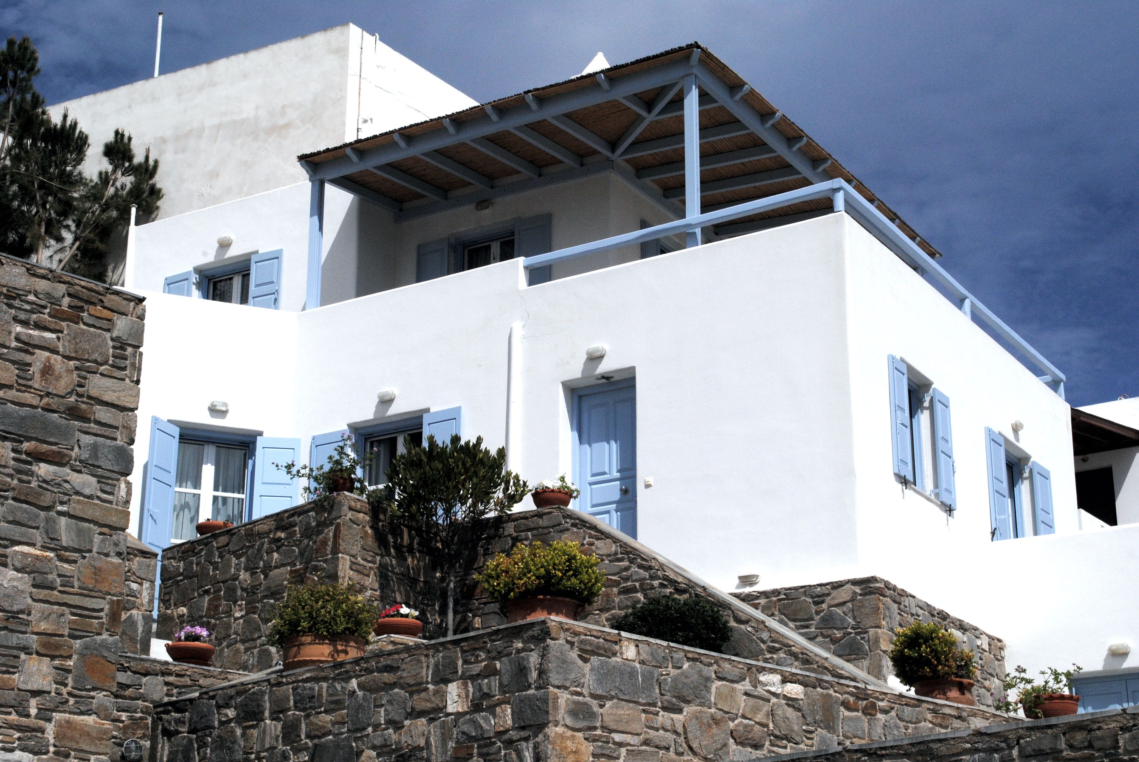 Madera Villa front facade general view stone stairs Spacious summer villa in white and light blue wooden windows and doors surrounded by grey stone walls, green gardens and ceramic amphoras